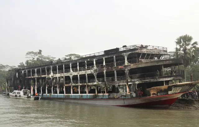 A burnt passenger ferry is seen anchored off the coast of Jhalokati district on the Sugandha River in Bangladesh, Friday, December 24, 2021. Bangladesh fire services say at least 37 passengers have been killed and many others injured in a massive fire that swept through a ferry on the southern Sugandha River. The blaze broke out around 3 a.m. Friday on the ferry packed with 800 passengers. (Photo by AP Photo/Stringer)