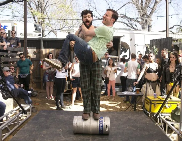 Keg balancing artist Nick Milan of Indianapolis carries audience member Ben Mang of New York City during his act at the Independence and Lagunitas Bug Out party at the Scoot Inn during South by Southwest Tuesday, March 14, 2017, in Austin, Texas. (Photo by Jay Janner/Austin American-Statesman via AP Photo)