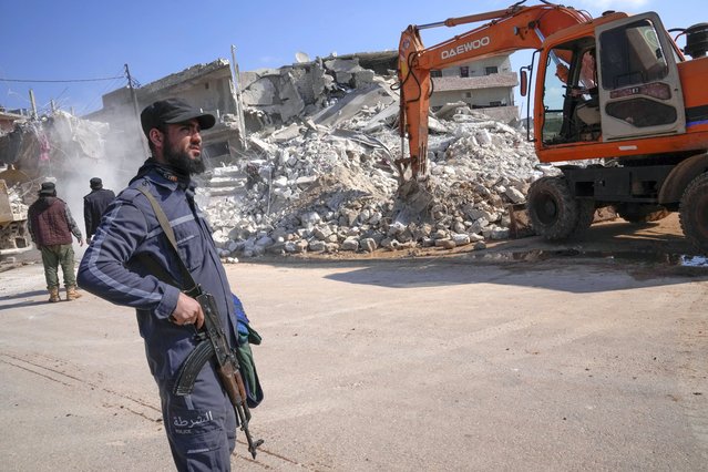 A militant of the al-Qaida-linked Hayat Tahrir al-Sham organisation stands in front of a destroyed house in Atareb, Syria, Sunday, February 12, 2023. Six days after a massive earthquake killed thousands in Syria and Turkey, sorrow and disbelief are turning to anger and tension over a sense that there has been an ineffective, unfair and disproportionate response to the historic disaster. (Photo by Hussein Malla/AP Photo)