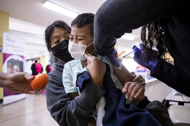 Sebastian, 6 years old, receives a dose of the Pfizer Covid-19 vaccine in the arms of his sister Valeria, 13 years old, at a pop-up vaccination clinic at the St. Bernadette Catholic Church during the coronavirus pandemic in Los Angeles, California, USA, 04 February 2022. (Photo by Etienne Laurent/EPA/EFE)