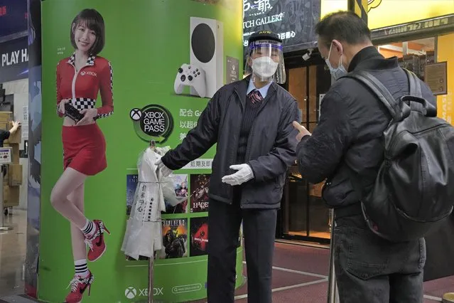 A worker wearing face mask, asks a man to scan the government's contact tracing QR code for the “LeaveHomeSafe” COVID-19 mobile app at an entrance of a shopping mall in Hong Kong, Thursday, February 17, 2022. Hong Kong on Thursday reported 6,116 new coronavirus infections, as the city’s hospitals reached 90% capacity and quarantine facilities are at their limit, authorities said. (Photo by Kin Cheung/AP Photo)