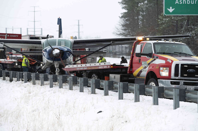 Southern Airways Express flight 246, which made an emergency landing on the Loudoun County Parkway, is pulled away from the guard rail it crashed into by a flatbed truck, Friday afternoon, January 19, 2024, in Dulles, Va., near Washington Dulles International Airport. There were seven people on board the single-engine Cessna 208 Caravan, according to Federal Aviation Administration, and no injuries were reported. (Photo by Clifford Owen/AP Photos)