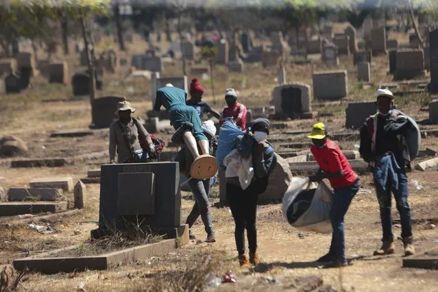 Zimbabwean vendors carry their wares in a cemetery after fleeing from the police who had chased them away after they were caught selling from undesignated areas due to COVID-19 restrictions in Harare, Thursday, July, 29, 2021.(Photo by Tsvangirayi Mukwazhi/AP Photo)