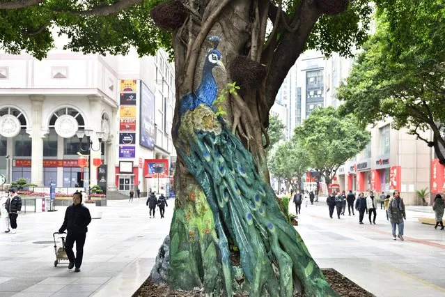 A tree trunk is painted with a peacock at Jiefangbei Pedestrian Street on February 22, 2022 in Chongqing, China. (Photo by VCG/VCG via Getty Images)