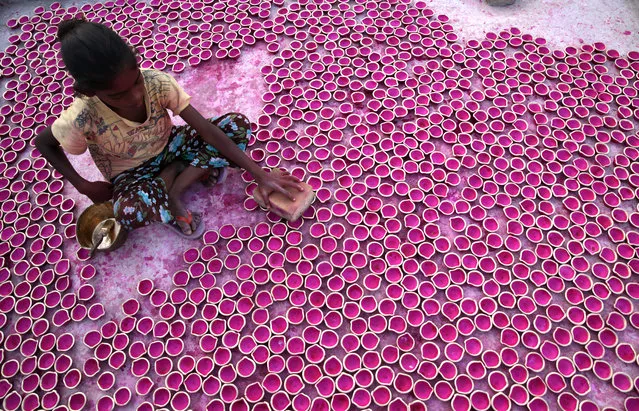 An Indian girl arranges freshly painted “Diya” or earthen lamps for drying at their home workshop, ahead of Diwali festival in Amritsar, India, 22 October 2019. Diya is a small earthen lamp primarily lit during Diwali, the festival of lights. Also known as Deep, Diya is traditionally made of clay. Lighting a Deep during Aarti ritual is a custom in the Hindu culture. During Diwali the earthen lamps are used for illuminating and to decorate the entire home and premises apart from Aarti. The Diya is filled with ghee or oil which works as fuel for it. This year the Diwali festival will be celebrated across the country on 27 October. (Photo by Raminder Pal Singh/EPA/EFE)