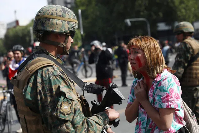 A demonstrator gestures in front of a soldier during a protest against the increase in subway ticket prices in Santiago, Chile, October 19, 2019. (Photo by Edgard Garrido/Reuters)