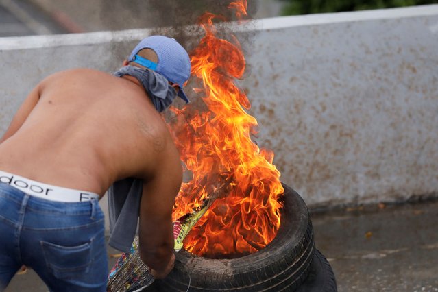 A protester sets a tyre on fire as supporters of Venezuelan opposition protest following the announcement by the National Electoral Council that Venezuela's President Nicolas Maduro won the presidential election, in Caracas, Venezuela on July 29, 2024. (Photo by Leonardo Fernandez Viloria/Reuters)