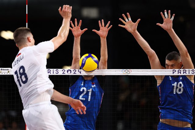 Clemen Cebulj of Slovenia, left, fires a shot that clips the net as Vuk Todorovic, centre, and Marko Podrascanin of Serbia defend in the mens’ volleyball preliminary round pool-A match at South Paris Arena 1 in  Paris, France on July 30, 2024. (Photo by Siphiwe Sibeko/Reuters)