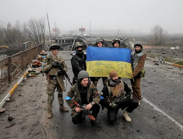 Ukrainian servicemen pose for a picture near a destroyed bridge as Russia's invasion of Ukraine continues, in the town of Irpin outside Kyiv on April 1, 2022. (Photo by Gleb Garanich/Reuters)