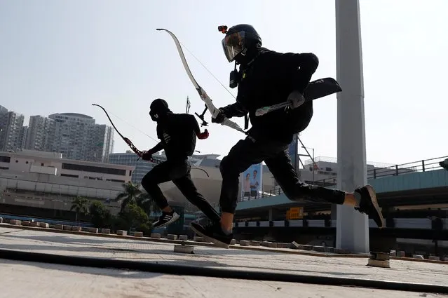 Protesters race with bows as they practice running away from riot police, on the roof of a bus shelter near the Cross Harbour Tunnel, which was blocked after demonstrators occupied the nearby Hong Kong Polytechnic University, in Hong Kong, November 15, 2019. Protesters have turned several universities into fortresses, stockpiled with petrol bombs and bows and arrows, amid some of the worst violence in the former British colony in decades. (Photo by Thomas Peter/Reuters)