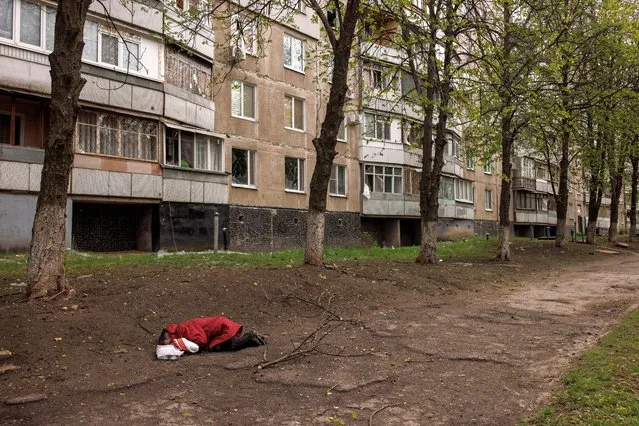 The body a woman lies next to an apartment block, following Russian shelling amid Russia's attack on Ukraine, in Kharkiv, Ukraine, April 19, 2022. (Photo by Alkis Konstantinidis/Reuters)