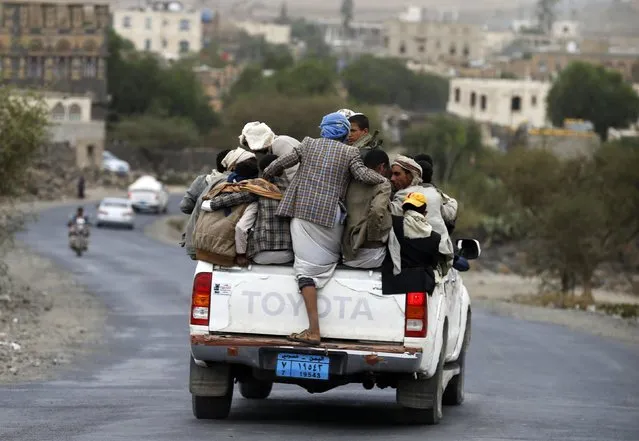 People ride on the back of a truck on a road linking Yemen's capital Sanaa with the northwestern city of Amran July 27, 2015. Fuel shortages in Yemen have caused hikes in taxi fees, forcing many to ride in overcrowded vehicles. (Photo by Khaled Abdullah/Reuters)