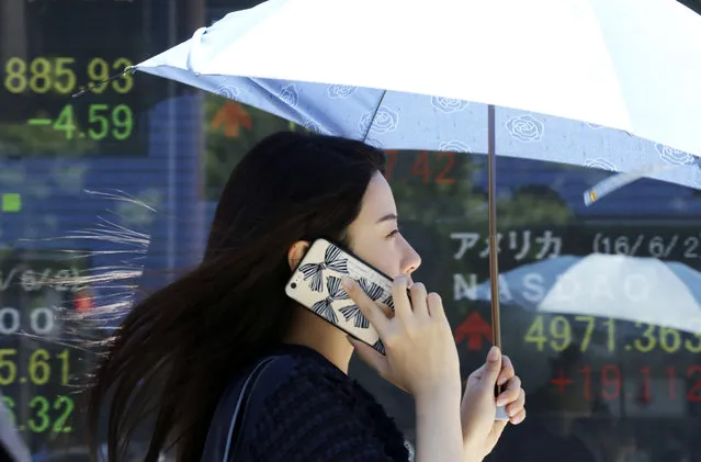 A woman walks by an electronic stock board of a securities firm in Tokyo, Friday, June 3, 2016. Asian shares were mixed Friday as investors awaited a U.S. jobs report later in the day and action from the U.S. Federal Reserve later in the month. (Photo by Koji Sasahara/AP Photo)
