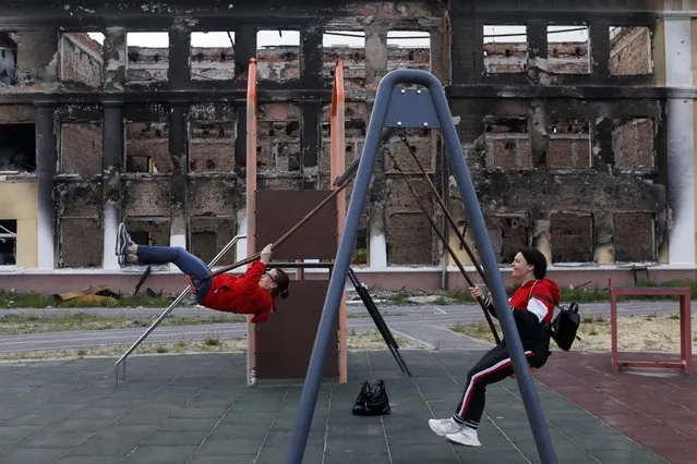 Former students Yana Shulyak and Olena Zhornik use a swing at the playground of a destroyed school, amid Russia's attack on Ukraine, in Kharkiv, Ukraine, May 14, 2022. (Photo by Ricardo Moraes/Reuters)