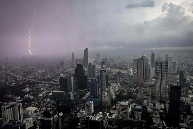 A bolt of lightning strikes the outskirts of Bangkok as the city skyline is pictured from the King Power Mahanakhon skyscraper in Bangkok on October 22, 2021. (Photo by Jack Taylor/AFP Photo)