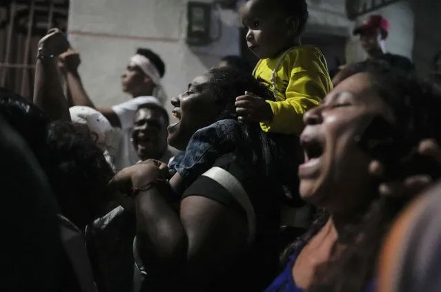 Residents chant during an overnight Catholic procession of a statue of San Juan Bautista, marking the start of a month-long celebration of the Saint in the neighborhood of San Agustin in Caracas, Venezuela, early Wednesday, June 1, 2022. The small statue of Saint John the Baptist, which was paraded through the streets, was in the custody of a family for the entire year and will be given to another family to protect until next year. (Photo by Ariana Cubillos/AP Photo)