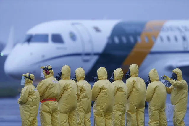 Soldiers wear protective suits during the arrival of Brazilians repatriated from Wuhan, China, the epicenter of the coronavirus, at the Annapolis Air Force Base, in Anapolis city, Goias state, Brazil, Sunday, February 9, 2020. Dozens of Brazilians landed early Sunday morning at the airbase in the Brazilian state of Goias, where they will spend the next 18 days in quarantine. (Photo by Beto Barata/AP Photo)