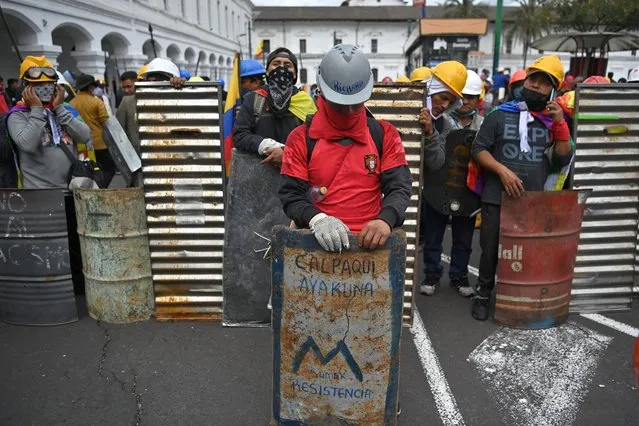 Indigenous people stand with makeshift shields at Santo Domingo square, in Quito, on June 27, 2022. Indigenous protesters in Ecuador vowed Monday to continue a disruptive country-wide protest against high living costs, rejecting a fuel price cut announced by the government as insufficient and “insensitive”. President Guillermo Lasso on Sunday announced a 10-cents-per-gallon reduction in fast-rising diesel and gasoline prices that sparked the uprising, now in its 15th day and severely hampering the oil-dependent economy. (Photo by Martin Bernetti/AFP Photo)