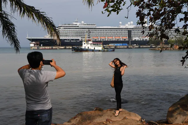 A woman has her picture taken in front of the Westerdam cruise ship in Sihanoukville on February 19, 2020. Cambodia's strongman premier has defended his decision to allow a US cruise ship to dock despite at least one passenger later being diagnosed with the deadly coronavirus, while authorities scrambled to track down hundreds that came in contact with her. (Photo by Tang Chhin Sothy/AFP Photo)