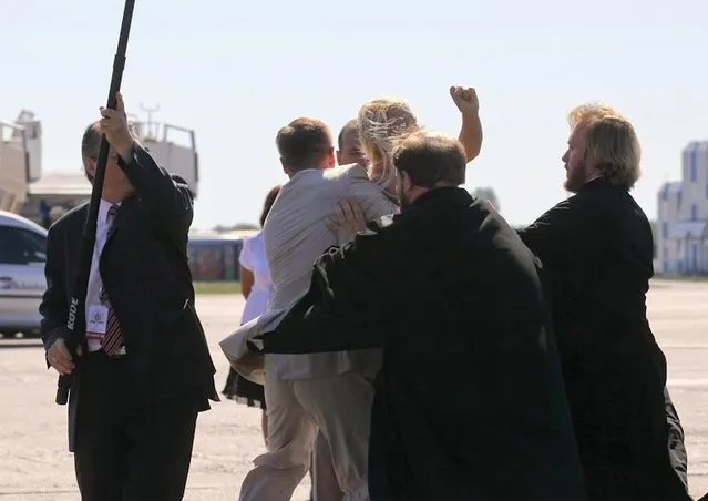 A topless protester from the Ukrainian feminist group Femen is blocked by a security guard and a priest as she tries to throw herself at the leader of the Russian Orthodox Church