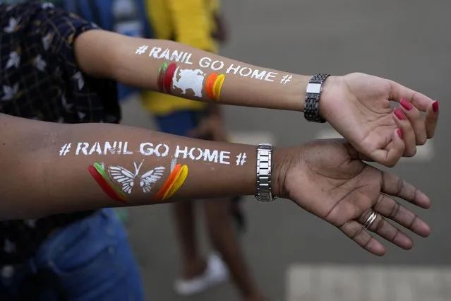 Girls display their arms painted with message “Ranil go home” referring to Prime Minister Ranil Wickremesinghe at the protest site in Colombo, Sri Lanka, July 17, 2022. (Photo by Rafiq Maqbool/AP Photo)