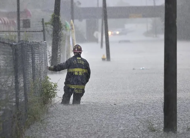 St. Louis firefighters checks on a car stalled out in chest-deep water flood water on Goodfellow Boulevard during a thunderstorm on Thursday, July 28, 2022, in St, Louis, Mo. (Photo by David Carson/St. Louis Post-Dispatch via AP Photo)