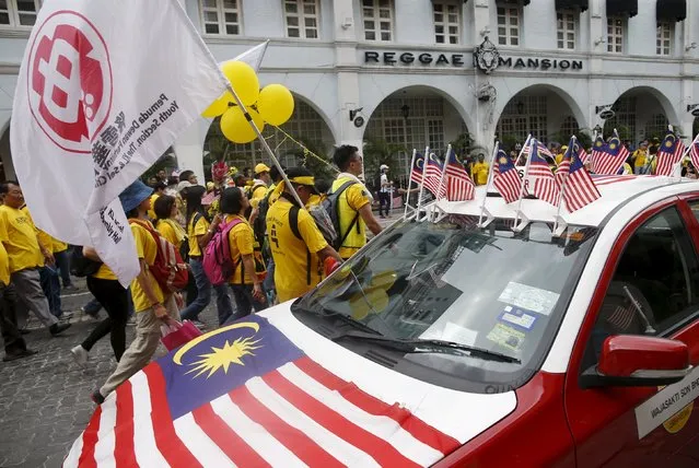Supporters of pro-democracy group “Bersih” (Clean) pass a taxi decorated with Malaysian flags as they march towards Dataran Mederka in Malaysia's capital city of Kuala Lumpur August 29, 2015. (Photo by Edgar Su/Reuters)