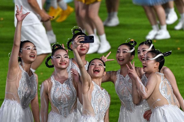 Performers take a selfie during the closing ceremony of the 2022 Asian Games at the Hangzhou Olympic Sports Centre Stadium in Hangzhou in China's eastern Zhejiang province on October 8, 2023. (Photo by Jung Yeon-Je/AFP Photo)