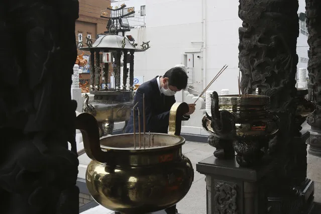 A man wearing a face mask to protect against the spread of the new coronavirus prays at a temple in Yokohama, near Tokyo Wednesday, April 22, 2020. (Photo by Koji Sasahara/AP Photo)