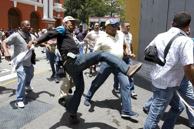 Supporters of Venezuela's President Nicolas Maduro clash with supporters of jailed opposition leader Leopoldo Lopez during a gathering outside the courthouse during his trial in Caracas September 10, 2015. (Photo by Carlos Garcia Rawlins/Reuters)