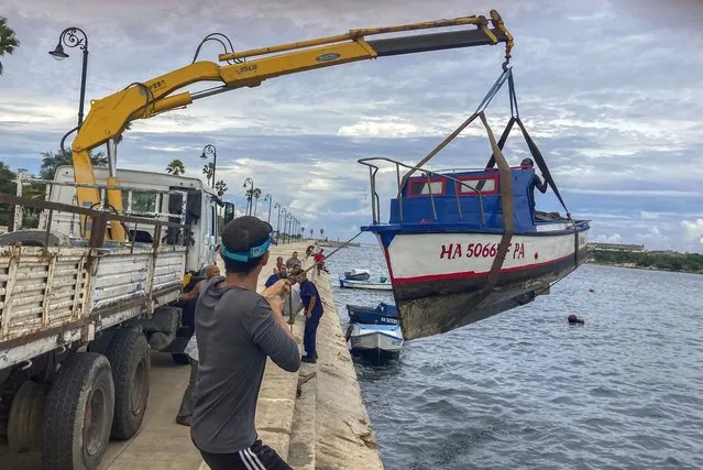 Workers remove a boat from the water in the bay of Havana, Cuba, Monday, September 26, 2022. (Photo by Milexsy Duran/AP Photo)