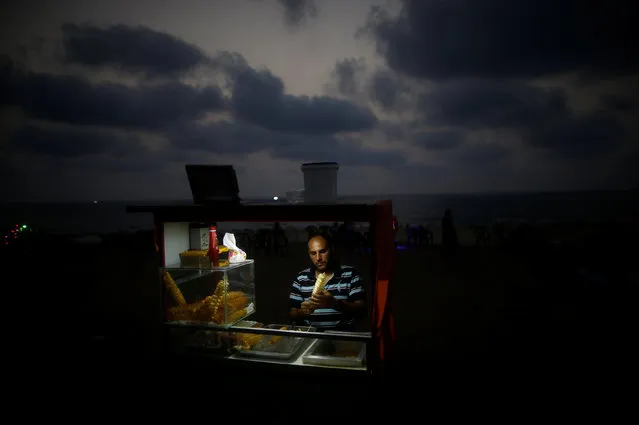 A Palestinian vendor sells snacks on a beach during a power cut as he uses battery-powered lights in Gaza City, July 12, 2017. (Photo by Mohammed Salem/Reuters)