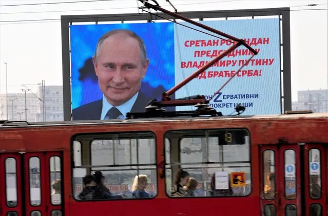 People look through the tram windows as they pass a big screen showing Russian President Vladimir Putin and reading: “Happy birthday to President Vladimir Putin from the Serb brethren!”, in Belgrade, Serbia, Friday, Ocober. 7, 2022. The posters are signed by a Pro-Russian right-wing group. Putin remains popular in Serbia despite the attack on Ukraine, and many in the Balkan country believe that the Russian president was provoked by the West into launching the invasion. (Photo by Darko Vojinovic/AP Photo)
