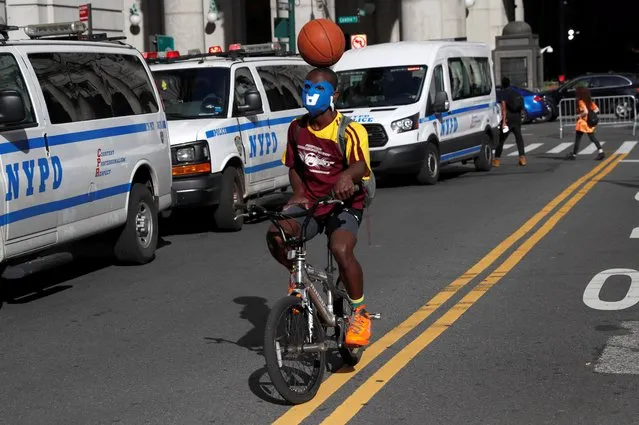 A man rides a bicycle as he balances a ball on his head during a protest against racial inequality in the aftermath of his death in Minneapolis police custody, in New York City, New York, U.S. June 8, 2020. (Photo by Shannon Stapleton/Reuters)