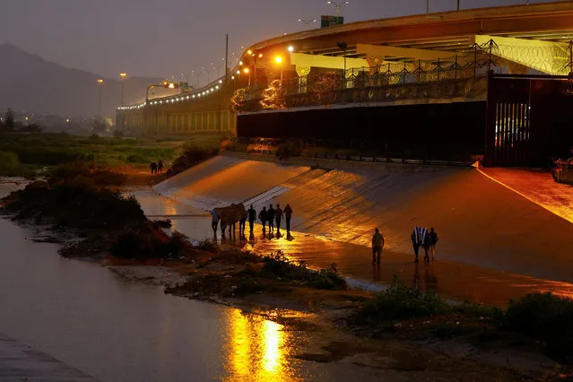 Asylum-seeking migrants walk near the border wall after crossing the Rio Bravo river to turn themselves in to U.S. Border Patrol agents to request asylum in El Paso, Texas, U.S., as seen from Ciudad Juarez, Mexico on October 6, 2022. (Photo by Jose Luis Gonzalez/Reuters)