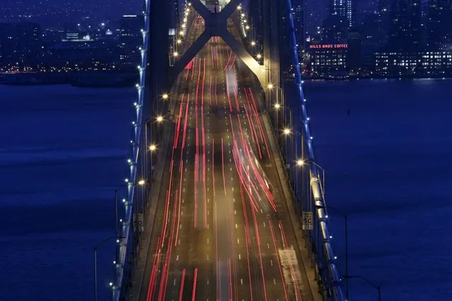 In this September 3, 2014, picture made with a long exposure, lights from evening rush hour traffic move over the San Francisco Oakland Bay Bridge in San Francisco. (Photo by Marcio Jose Sanchez/AP Photo)
