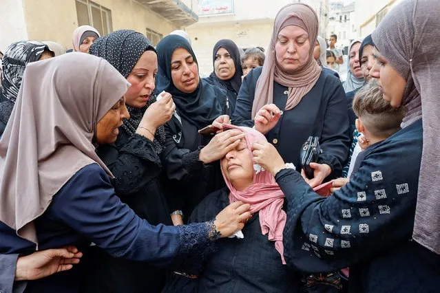 Mourners console the mother of Palestinian Mateen Dbaya, who was killed following an Israeli forces raid in Jenin refugee camp, during his funeral, in the Israeli-occupied West Bank on October 14, 2022. (Photo by Raneen Sawafta/Reuters)