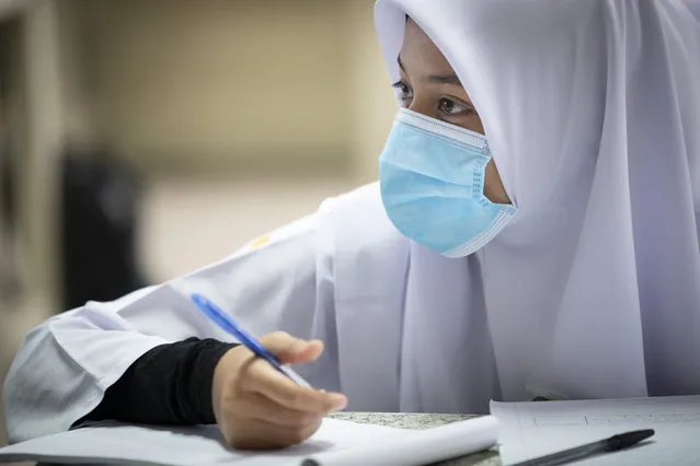 A student wearing a face mask takes a class during the first day of school reopening at a high school in Putrajaya, Malaysia, Wednesday, June 24, 2020. Malaysia began reopening schools Wednesday while entering the Recovery Movement Control Order (RMCO) after three months of coronavirus restrictions. (Photo by Vincent Thian/AP Photo)