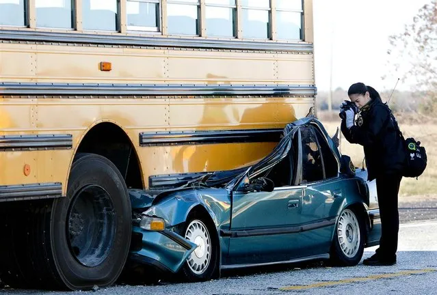 An investigator photographs the aftermath of a fatal bus accident on December 12, in Hockley, Texas. Authorities said the driver of the car died; the three children and driver on the bus were not injured. The cause of the accident is under investigation. (Photo by Cody Duty / Houston Chronicle via AP)