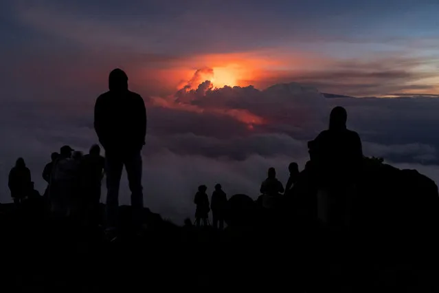 People gather to watch the eruption of the Mauna Loa Volcano while the lava flow is covered with the clouds in Hawaii, U.S. December 3, 2022. (Photo by Go Nakamura/Reuters)