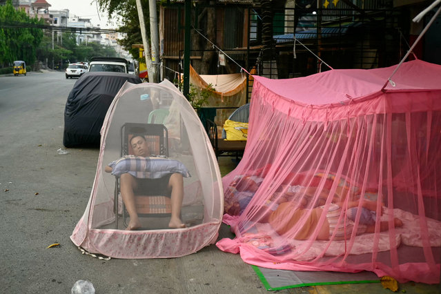 People sleep under mosquito nets on the street in Mandalay on April 4, 2025. (Photo by Sai Aung Main/AFP Photo)