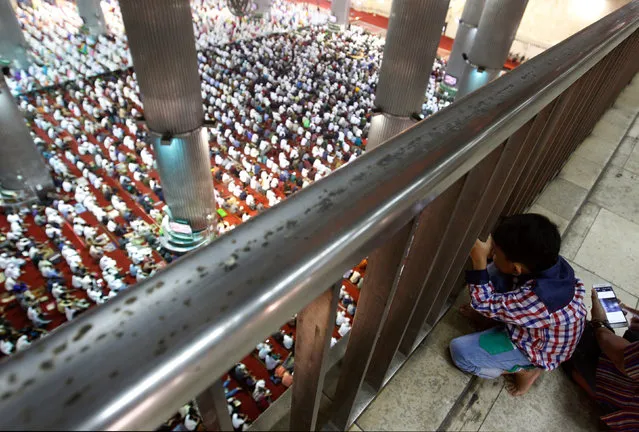A boy watches people attending prayers for the Muslim holiday of Eid Al-Adha at Istiqlal Mosque in Jakarta, Indonesia September 12, 2016. (Photo by Iqro Rinaldi/Reuters)