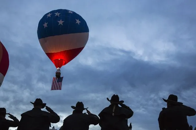 Police officers salute as the Star Spangled Banner is played to mark the beginning of a lift off during the 2015 Albuquerque International Balloon Fiesta in Albuquerque, New Mexico, October 7, 2015. (Photo by Lucas Jackson/Reuters)