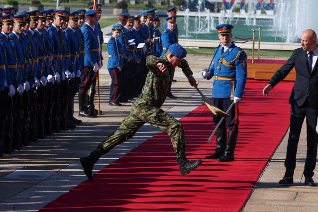 A soldier holding a broom jumps over the red carpet ahead of the welcoming ceremony for the European Council President Antonio Costa, in Belgrade, Serbia, on May 13, 2025. (Photo by Zorana Jevtic/Reuters)