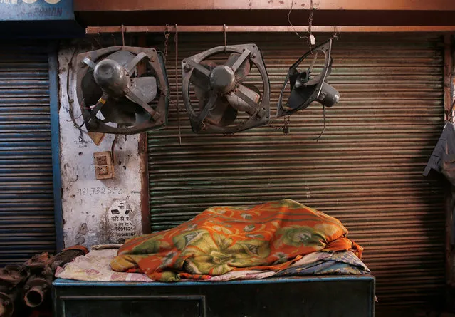 A man wrapped in a blanket sleeps outside a closed shop on a cold winter morning in the old quarters of Delhi, January 10, 2018. (Photo by Adnan Abidi/Reuters)