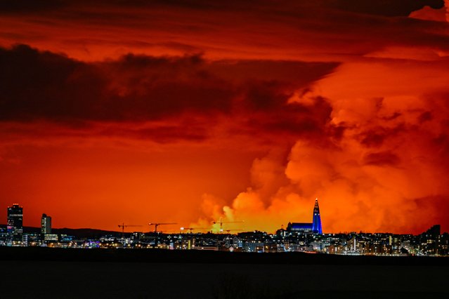 The skyline of Reykjavik is against the backdrop of orange coloured sky due to molten lava flowing out from a fissure on the Reykjanes peninsula north of the evacuated town of Grindavik, western Iceland on March 16, 2024. Lava spewed Saturday from a new volcanic fissure on Iceland's Reykjanes peninsula, the fourth eruption to hit the area since December, authorities said. (Photo by Halldor Kolbeins/AFP Photo)
