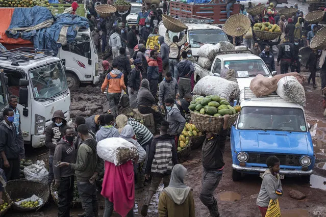 Traders carry baskets of vegetables through muddy pathways in Atkilt Tera, the largest open-air vegetable market, in the capital Addis Ababa, Ethiopia Thursday, September 10, 2020. (Photo by Mulugeta Ayene/AP Photo)