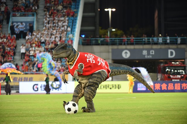 Simulated dinosaur storms the field to cheer for players prior to the Jiangsu Football City League (JSCL) ninth round match between Changzhou and Zhenjiang at Changzhou Olympic Sports Centre on August 16, 2025 in Changzhou, Jiangsu Province of China. The JSCL, also known as Su Super League or Su Chao in Chinese, has recently gone viral. The grassroots football match features 13 teams named after their respective cities in Jiangsu Province. (Photo by Liu Jianmin/VCG via Getty Images)