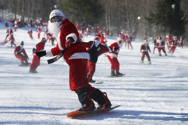 Skiers and snowboarders dressed as Santa Claus participate in a charity run down a slope at Sunday River Ski Resort in Newry, Maine December 7, 2014. Organizers say 250 skiing Santas raised $2700 for charity at the event. (Photo by Brian Snyder/Reuters)