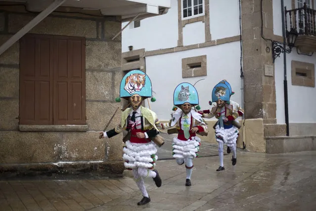 Carnival revelers dressed as “Peliqueiros” run through a street in Spain's northwestern village of Laza, on February 10, 2013. “Peliqueiros” or ancient tax collectors, pursued villagers through the streets ringing their cowbells and hitting villagers with their sticks. (Photo by Miguel Vidal/Reuters /The Atlantic)
